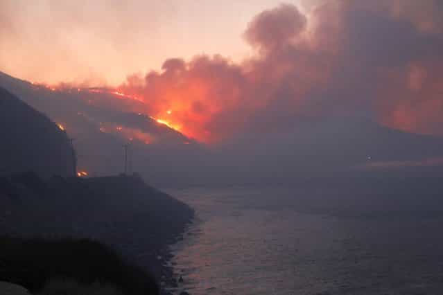 The Springs Fire burns in the early morning near Pacific Coast Highway at Point Mugu State Park, May 3, 2013. A wind-driven wildfire raging along the California coast north of Los Angeles prompted the evacuation of hundreds of homes and a university campus on Thursday as flames engulfed several farm buildings and recreational vehicles near threatened neighborhoods. (Photo by Jonathan Alcorn/Reuters)