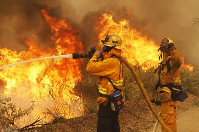 Firefighters battle the Springs Fire at Point Mugu State Park May 3, 2013. A wind-driven wildfire raged along the California coast north of Los Angeles early on Friday, threatening some 3,000 homes and prompting evacuations of a university campus and several residential areas. The so-called Springs Fire, which engulfed several farm buildings and recreational vehicles but so far has destroyed no homes, had consumed 8,000 acres of dry, dense chaparral and brush by late Thursday, fire officials said. (Photo by Jonathan Alcorn/Reuters)