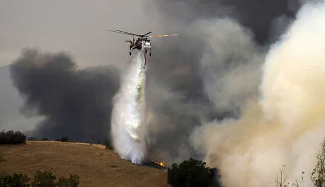 A Skycrane fire-fighting helicopter makes a water drop on the second day of the Springs Fire in the mountain areas of Ventura County, California May 3, 2013. A fierce, wind-whipped wildfire spread on Friday along the California coast northwest of Los Angeles, threatening several thousand homes and a military base as more than 1,100 dwellings were ordered evacuated and a university campus was closed. (Photo by Gene Blevins/Reuters)