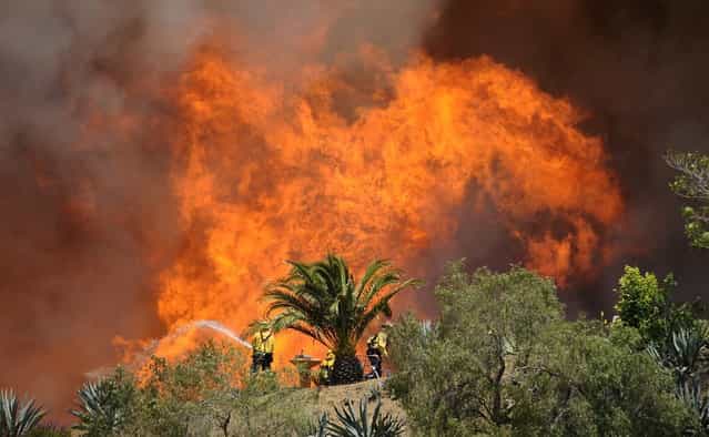 Fire-fighters battle walls of flames to protect homes during the second day of the Springs Fire in the mountain areas of Ventura County, California May 3, 2013. A fierce, wind-whipped brush wildfire spread on Friday along the California coast northwest of Los Angeles, threatening several thousand homes and a military base as more than 1,100 dwellings were ordered evacuated and a university campus was closed. (Photo by Gene Blevins/Reuters)