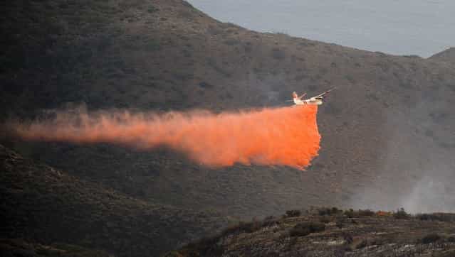 A air tanker drops fire retardant on the Springs Fire near Malibu, California May 3, 2013. A fierce, wind-whipped wildfire spread on Friday along the California coast northwest of Los Angeles, threatening 4,000 homes and a military base as residents were evacuated ahead of the flames and a university campus was closed. (Photo by Gus Ruelas/Reuters)