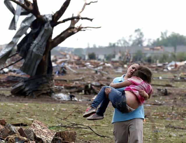 A woman carries a child through a field near the collapsed Plaza Towers Elementary School in Moore, Oklahoma. (Photo by Sue Ogrocki/Associated Press)