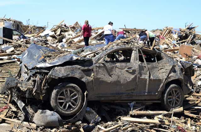 People salvage belongings at a tornado devastated home on May 22, 2013 in Moore, Oklahoma. As rescue efforts in Oklahoma wound down, residents turned to the daunting task of rebuilding a US heartland community shattered by a vast tornado that killed at least 24 people. The epic twister, two miles (three kilometers) across, flattened block after block of homes as it struck mid-afternoon on May 20, hurling cars through the air, downing power lines and setting off localized fires in a 45-minute rampage. (Photo by Jewel Samad/AFP Photo)