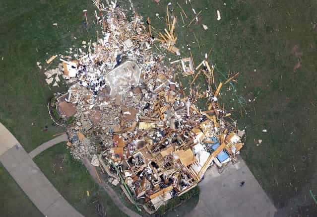 In this aerial photo, a person, lower right, stand in front of a home demolished home by Monday's tornado, in Moore, Okla., Tuesday, May 21, 2013. The huge tornado roared through the Oklahoma City suburb Monday, flattening entire neighborhoods and destroying an elementary school with a direct blow as children and teachers huddled against winds. (Photo by Tony Gutierrez/AP Photo)