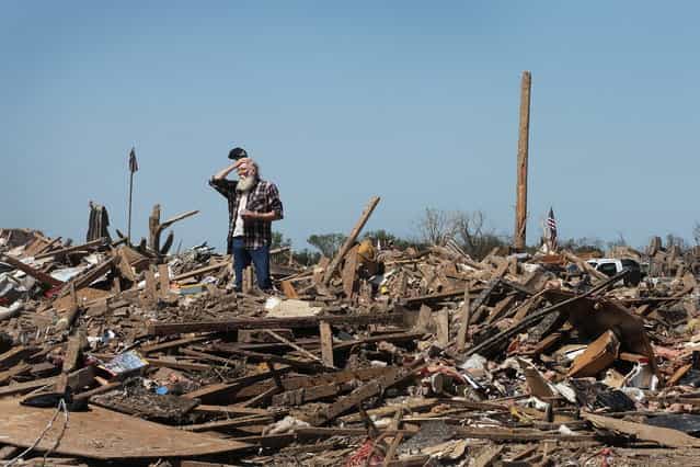 John Wilson surveys the neighborhood from atop the rubble that was once a home that his son and ex-wife shared before the home and the neighborhood were destroyed by a tornado that ripped through the area on May 22, 2013 in Moore, Oklahoma. The tornado of at least EF4 strength and two miles wide touched down May 20 killing at least 24 people and leaving behind extensive damage to homes and businesses. U.S. President Barack Obama promised federal aid to supplement state and local recovery efforts. (Photo by Scott Olson/AFP Photo)