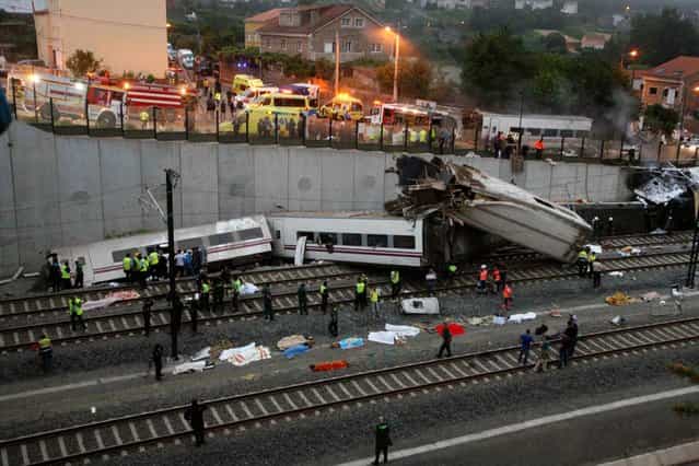 Emergency personnel respond to the scene of a train derailment in Santiago de Compostela, Spain, on Wednesday, July 24, 2013. A train derailed in northwestern Spain on Wednesday night, toppling passenger cars on their sides and leaving at least one torn open as smoke rose into the air. Dozens were feared dead, with possibly even more injured. (Photo by Antonio Hernandez/AP Photo/El correo Gallego)