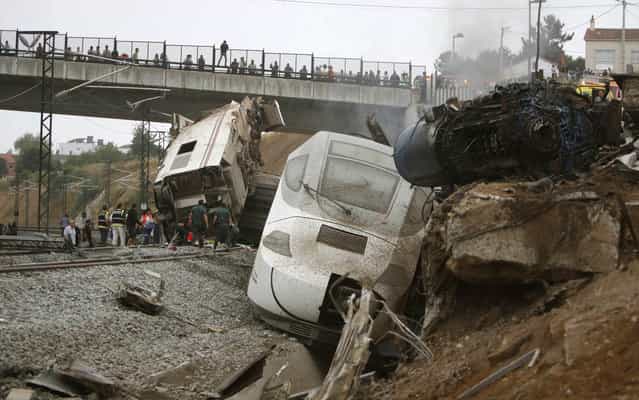 Emergency personnel respond to the scene of a train derailment in Santiago de Compostela, Spain, on Wednesday, July 24, 2013. A train derailed in northwestern Spain on Wednesday night, toppling passenger cars on their sides and leaving at least one torn open as smoke rose into the air. Dozens were feared dead, with possibly even more injured. (Photo by Antonio Hernandez/AP Photo/El correo Gallego)