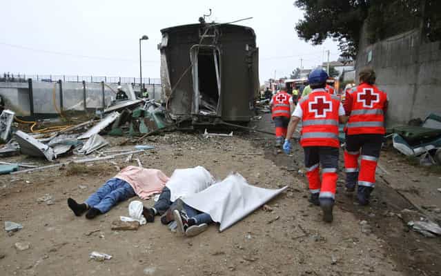 Emergency personnel respond to the scene of a train derailment in Santiago de Compostela, Spain, Wednesday, July 24, 2013. A train derailed in northwestern Spain on Wednesday night, toppling passenger cars on their sides and leaving at least one torn open as smoke rose into the air. Dozens were feared dead, with possibly even more injured. (Photo by Antonio Hernandez/AP Photo/El correo Gallego)