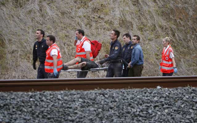 A man is evacuated by emergency personnel at the scene of a train derailment in Santiago de Compostela, Spain, on Wednesday, July 24, 2013. A train derailed in northwestern Spain on Wednesday night, toppling passenger cars on their sides and leaving at least one torn open as smoke rose into the air. Dozens were feared dead, with possibly even more injured. (Photo by Antonio Hernandez/AP Photo/El correo Gallego)