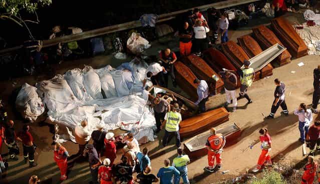 Coffins are lined up near the wreckage of the bus, on July 29, 2013. (Photo by Salvatore Laporta/Associated Press)