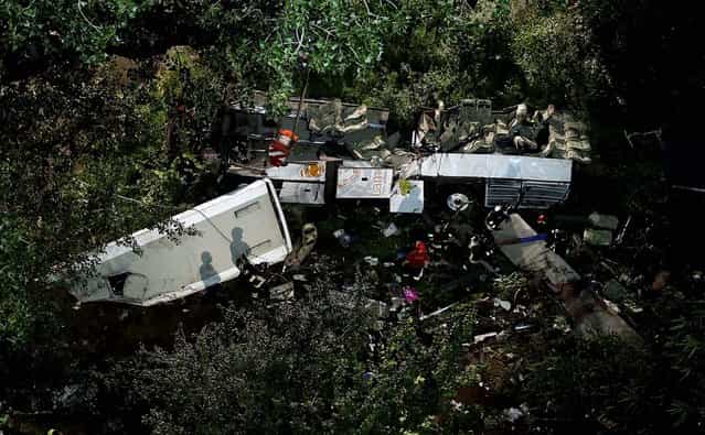 Firefighters work on the wreckage of a bus that plunged off the A16 highway near Avellino in southern Italy, on July 29, 2013. The tour bus filled with Italians returning home after an excursion plunged off the highway into a ravine Sunday night after it smashed into several cars that were slowed by heavy traffic. At least 37 people died in the accident. (Photo by Gregorio Borgia/Associated Press)