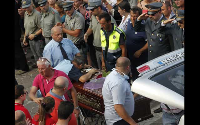 A relative of a victim of a coach crash reacts as gravediggers carry the coffin outside a gym, where all the bodies were gathered to be claimed, in Monteforte Irpino near Avellino July 29, 2013. (Photo by Ciro De Luca/Reuters)