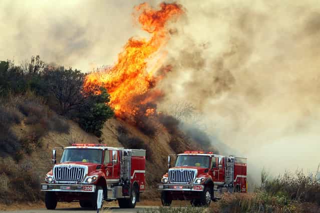 Flames from the Falls Fire burn on a hillside along South Main Divide Road in the Cleveland National Forest as firefighters drive through the area on Monday, August 5, 2013. (Photo by Kurt Miller/AP Photo/The Press-Enterprise)