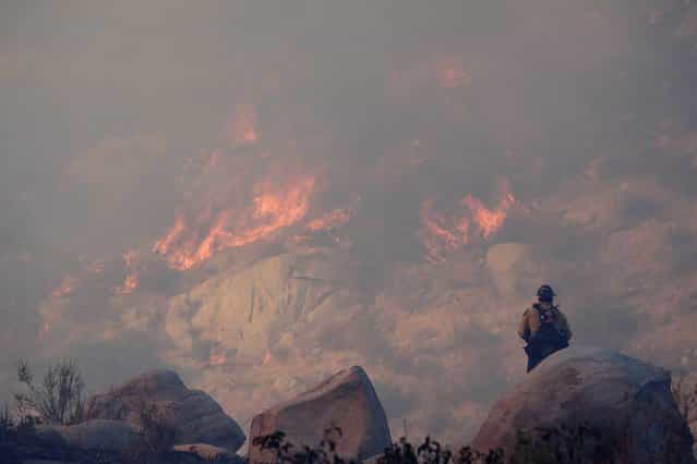 A firefighter watches a backfire burn while battling a wildfire, Thursday, August 8, 2013, in Banning, Calif. About 1,500 people have fled and three are injured as the wildfire in the Southern California mountains quickly spreads. Several small communities have evacuated. (Photo by Jae C. Hong/AP Photo)