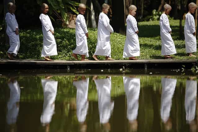 Novice nuns walk in the garden of the Sathira-Dhammasathan Buddhist meditation centre in Bangkok April 21, 2013. A group of Thai girls are choosing to spend part of their school holidays as Buddhist nuns, down to having their heads shaven at the meditation centre. The centre, founded in 1987, is a learning community for peace and harmony that has programs open to people regardless of age and gender. (Photo by Damir Sagolj/Reuters)