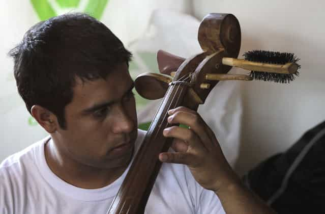 Music student Hugo Irrazabal plays his cello made from recycled materials during a rehearsal of the Orchestra of Recycled Instruments of Cateura, at the Vy'a Renda education center in Cateura, near Asuncion, May 8, 2013. The orchestra is the brainchild of its conductor Favio Chavez, who wanted to help the children of garbage pickers at the local landfill, and the instruments are made from salvaged materials by craftsman Nicolas Gomez. The orchestra now involves 30 schoolchildren who have toured countries in Latin America, North America and Europe to play music ranging from Beethoven and Mozart to the Beatles and Paraguayan folk songs. (Photo by Jorge Adorno/Reuters)