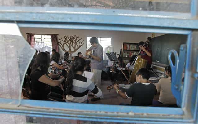 Director of the Orchestra of Recycled Instruments of Cateura, Favio Chavez (C, gray shirt), leads his music students during a rehearsal at the Vy'a Renda education center in Cateura, near Asuncion, May 8, 2013. The orchestra is the brainchild of its conductor Favio Chavez, who wanted to help the children of garbage pickers at the local landfill, and the instruments are made from salvaged materials by craftsman Nicolas Gomez. The orchestra now involves 30 schoolchildren who have toured countries in Latin America, North America and Europe to play music ranging from Beethoven and Mozart to the Beatles and Paraguayan folk songs. (Photo by Jorge Adorno/Reuters)