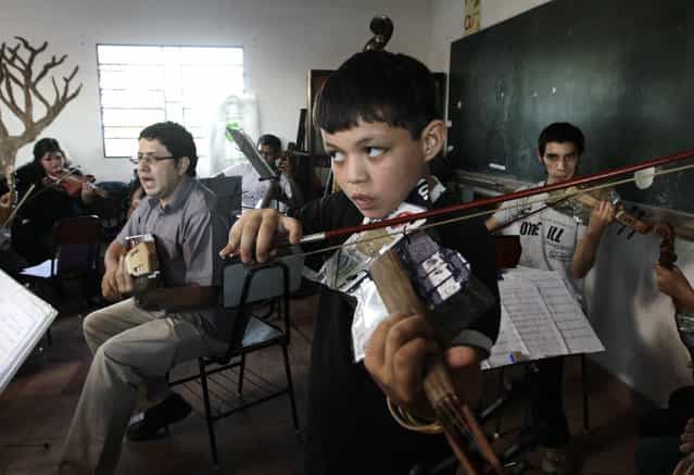 Director of the Orchestra of Recycled Instruments of Cateura, Favio Chavez (L, gray shirt), leads his music students during a rehearsal at the Vy'a Renda education center in Cateura, near Asuncion, May 8, 2013. The orchestra is the brainchild of its conductor Favio Chavez, who wanted to help the children of garbage pickers at the local landfill, and the instruments are made from salvaged materials by craftsman Nicolas Gomez. The orchestra now involves 30 schoolchildren who have toured countries in Latin America, North America and Europe to play music ranging from Beethoven and Mozart to the Beatles and Paraguayan folk songs. (Photo by Jorge Adorno/Reuters)
