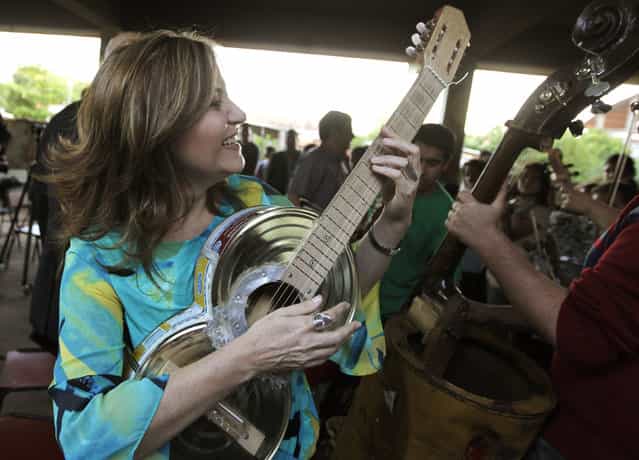 Renowned Paraguayan classical guitarist, Bertha Rojas, plays an instrument made from recycled food tins by craftsman Nicolas Gomez, during a visit to the Orchestra of Recycled Instruments of Cateura in Cateura, near Asuncion, May 9, 2013. The orchestra is the brainchild of its conductor Favio Chavez, who wanted to help the children of garbage pickers at the local landfill, and the instruments are made from salvaged materials by craftsman Gomez. The orchestra now involves 30 schoolchildren who have toured countries in Latin America, North America and Europe to play music ranging from Beethoven and Mozart to the Beatles and Paraguayan folk songs. (Photo by Jorge Adorno/Reuters)