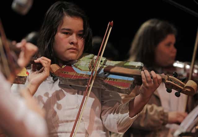 Music student Valencia plays a violin made from recycled objects during a concert of the Orchestra of Recycled Instruments of Cateura, in Asuncion, June 22, 2013. The orchestra is the brainchild of its conductor Favio Chavez, who wanted to help the children of garbage pickers at the local landfill, and the instruments are made from salvaged materials by craftsman Nicolas Gomez. The orchestra now involves 30 schoolchildren who have toured countries in Latin America, North America and Europe to play music ranging from Beethoven and Mozart to the Beatles and Paraguayan folk songs. (Photo by Jorge Adorno/Reuters)