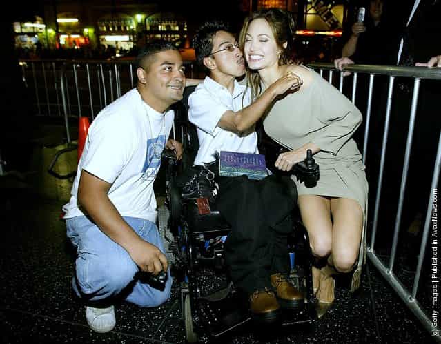 Actress Angelina Jolie signs autographs for a man in a wheelchair