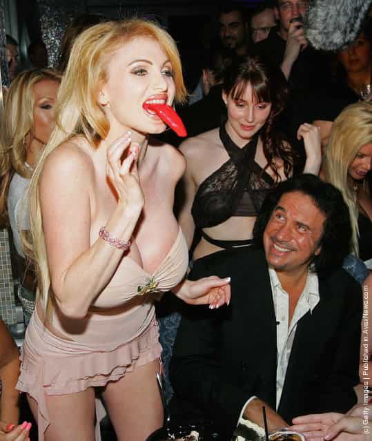 Kiss singer/bassist Gene Simmons watches as adult film actresses Sara Jay (L) and Taylor Wane play with the tongue from his birthday cake during his birthday party at the Palms Casino