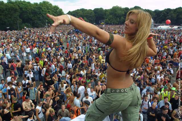A woman dances on top of a truck blaring techno music to thousands of ravers during the annual Love Parade