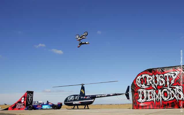 Australian Motorcross rider and member of the Crusty Demons, Robbie Marshall jumps over a helicopter with rotating blades and a Formula 1 car at Avalon Airport