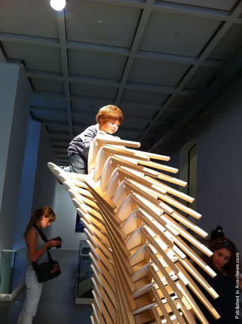 Boy climbing chairs By Patricia Piccinini