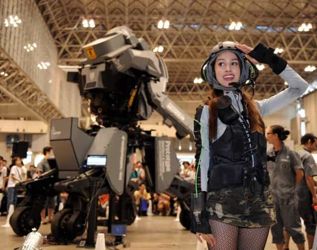 Female [pilot] Anna (R) salutes after demonstrating Japanese electronics company Suidobashi Heavy Industrys newly unveiled robot [Kuratas] at the Wonder Festival in Chiba, suburban Tokyo on July 29, 2012. The Kuratas robot, which will go on sale with a price tag of one million USD, measures four meters in height, weighs four tons and has four wheeled legs that can either be controlled remotely through the 3G network or by a human seated within the cockpit.