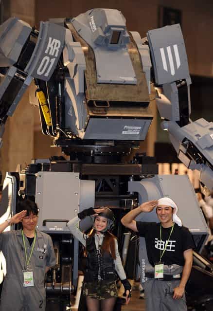 Engineers Wataru Yoshizaki (L), Mitsugoro Kurata (R) and pilot Anna (C) pose in front of Japanese electronics company Suidobashi Heavy Industrys newly unveiled robot [Kuratas] at the Wonder Festival in Chiba, suburban Tokyo on July 29, 2012. The Kuratas robot, which will go on sale with a price tag of one million USD, measures four meters in height, weighs four tons and has four wheeled legs that can either be controlled remotely through the 3G network or by a human seated within the cockpit.