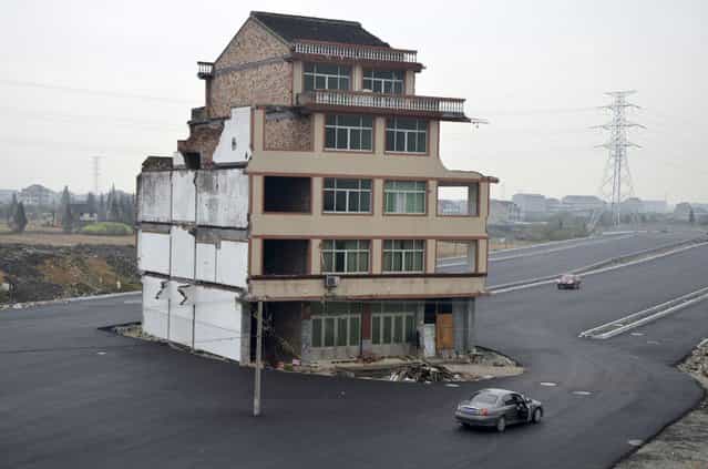 An isolated five-floor building stands in the middle of a new road on November 22, 2012 in Wenling, Zhejiang Province of China. Zhejiang Province of China. 67-year-old Luo Baogen and his 65-year-old wife from Xiazhangyang village still live in the half-demolished residential building, because they are dissatisfied with the relocation compensation. The road, which leads to the Wenling Railway Station, has not been put into use. (Photo by ChinaFotoPress)
