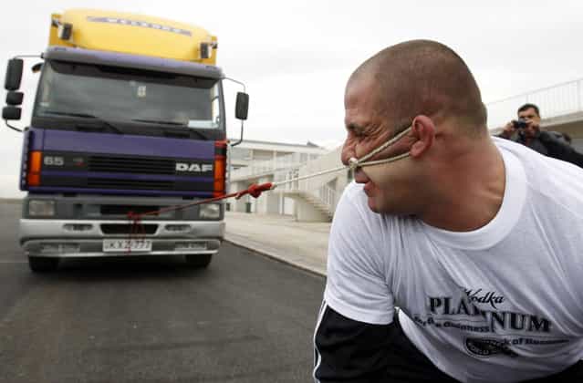 Lasha Pataraia pulls an eight-ton truck with his ear during a test event in Rustavi outside Tbilisi November 14, 2012. The 32-year-old sportsman will attempt to break a record registered by the Guinness Book of World Records by the end of the month, according to organisers. REUTERS/David Mdzinarishvili (GEORGIA - Tags: SOCIETY TPX IMAGES OF THE DAY)