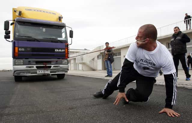 Lasha Pataraia pulls an eight-ton truck with his ear during a test event in Rustavi outside Tbilisi November 14, 2012. The 32-year-old sportsman will attempt to break a record registered by the Guinness Book of World Records by the end of the month, according to organisers. (Photo by David Mdzinarishvili/Reuters)