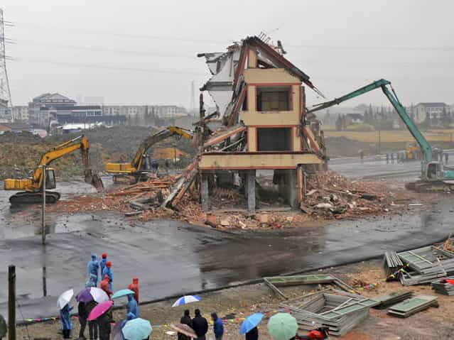 Excavators are used to demolish a house standing alone in the middle of a newly built road in Wenling, Zhejiang province December 1, 2012. Luo Baogen, the owner of the house, who earlier refused to sign an agreement to allow his house to be demolished, finally signed the agreement after discussions with the local government and his relatives, after Baogen agreed to accept compensation of 260,000 yuan ($41,000). The demolition of the house started this Saturday, local media reported. (Photo by China Daily/Reuters)