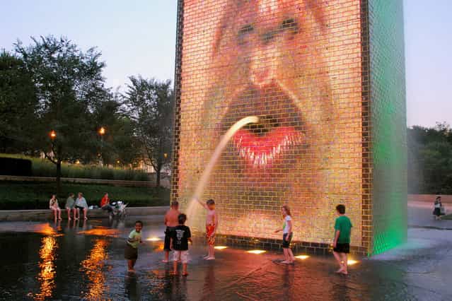 [Recycling]. A stream of water coming out of the mouth of one of the two video faces, splashing into the shallow pool. Crown Fountain, Millennium Park, Chicago, IL. (Photo by M.V. Jantzen)