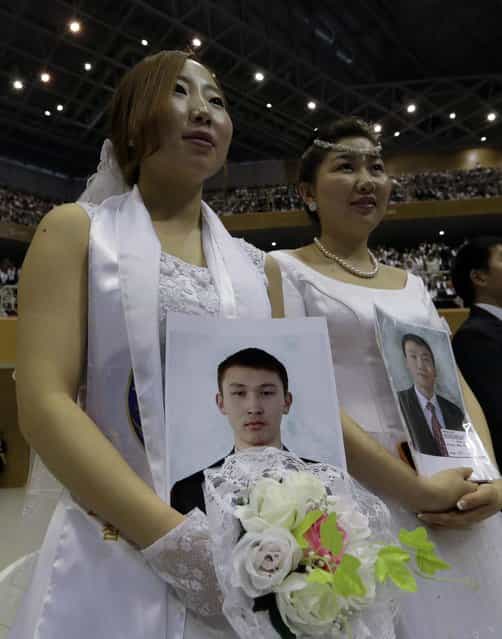 Mongolian bride Enkhzul Baatarchuluun, left, holds the picture of her groom Otgonbold Myagmardorj from Mongolia, who didn't appear, in a mass wedding ceremony at the CheongShim Peace World Center in Gapyeong, South Korea, Sunday, February 17, 2013. Some 3,500 South Korean and foreign couples exchanged or reaffirmed marriage vows in the Unification Church's mass wedding arranged by Hak Ja Han Moon, a wife of the late Rev. Sun Myung Moon, the controversial founder of the Unification Church. (Photo by Lee Jin-man/AP Photo)