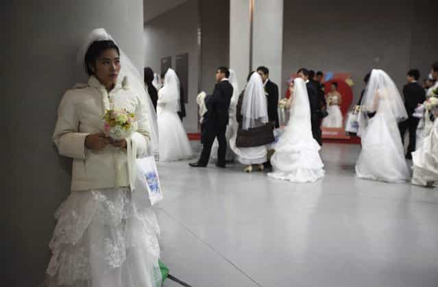 A bride waits for her groom during a mass wedding ceremony of the Unification Church at Cheongshim Peace World Centre in Gapyeong, about 60 km (37 miles) northeast of Seoul February 17, 2013. The Unification Church founded by evangelist reverend Moon Sun-myung in Seoul in 1954, performed its first mass wedding in 1961 with 33 couples. Approximately 3,500 couples attended the mass wedding on Sunday. (Photo by Kim Hong-Ji/Reuters)