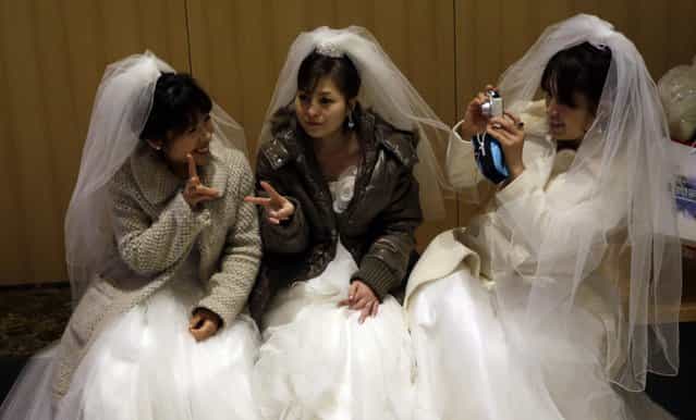 Brides take their souvenir pictures each others before their mass wedding ceremony at the CheongShim Peace World Center in Gapyeong, South Korea, Sunday, February 17, 2013. Some 3,500 South Korean and foreign couples exchanged or reaffirmed marriage vows in the Unification Church's mass wedding arranged by Hak Ja Han Moon, a wife of the late Rev. Sun Myung Moon, the controversial founder of the Unification Church. (Photo by Lee Jin-man/AP Photo)