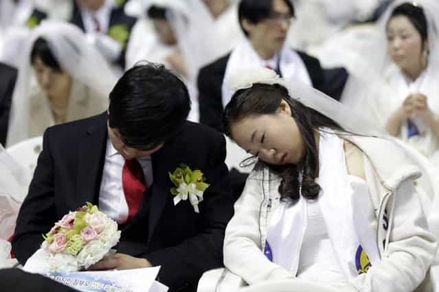 A newly-married couple takes a nap before their mass wedding ceremony at the CheongShim Peace World Center in Gapyeong, South Korea, Sunday, February 17, 2013. Some 3,500 South Korean and foreign couples exchanged or reaffirmed marriage vows in the Unification Church's mass wedding arranged by Hak Ja Han Moon, a wife of the late Rev. Sun Myung Moon, the controversial founder of the Unification Church. (Photo by Lee Jin-man/AP Photo)