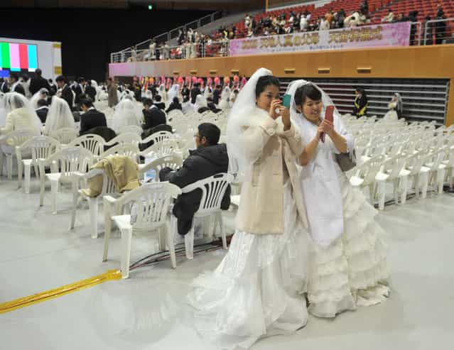 Two brides look at their mobile phones during a mass wedding organised by the Unification Church in Gapyeong on February 17, 2013. Some 3,500 couples married in a mass wedding organised by the Unification Church on February 17 – the first such event since the death of their "messiah" and controversial church founder Sun Myung Moon. (Photo by Kim Jae-Hwan/AFP Photo)