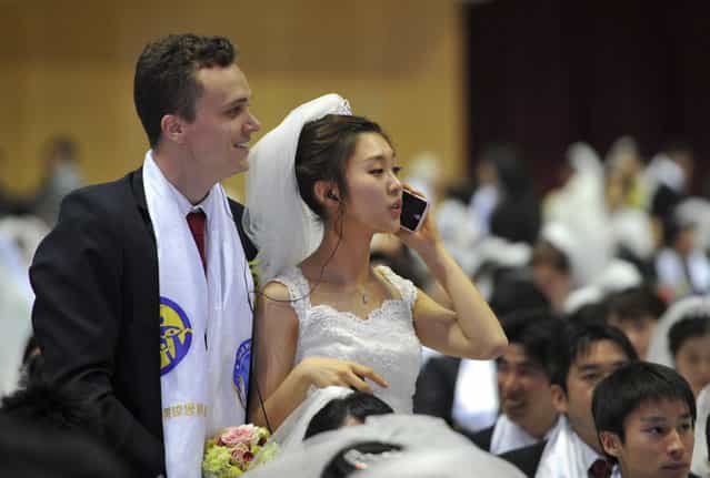 A newly-married bride talks on the phone during a mass wedding of the Unification Church held in the church's headquarters in Gapyeong, east of Seoul, on February 17, 2013. The Unification Church, set up by Sun Myung Moon in Seoul in 1954, is one of the world's most controversial religious organisations, and its devotees are often dubbed [Moonies] after the founder. (Photo by Kim Jae-Hwan/AFP Photo)