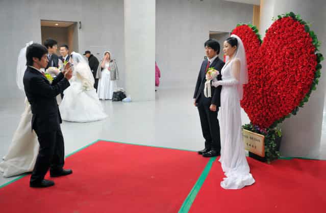 A couple has their photograph taken during a mass wedding organised by the Unification Church in Gapyeong on February 17, 2013. Some 3,500 couples married in a mass wedding organised by the Unification Church on February 17 – the first such event since the death of their "messiah" and controversial church founder Sun Myung Moon. (Photo by Kim Jae-Hwan/AFP Photo)
