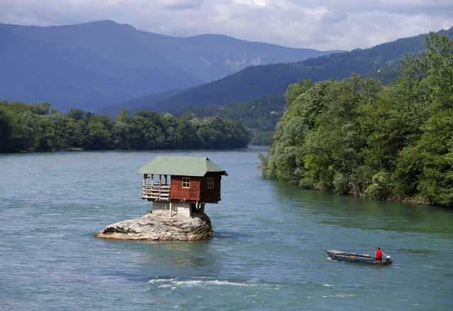 A man rows a boat near a house built on a rock on the river Drina near the western Serbian town of Bajina Basta, about 160km (99 miles) from the capital Belgrade May 22, 2013. (Photo by Marko Djurica/Reuters)