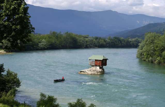 A man rows a boat near a house built on a rock on the river Drina near the western Serbian town of Bajina Basta, about 160km (99 miles) from the capital Belgrade May 22, 2013. The house was built in 1968 by a group of young men who decided that the rock on the river was an ideal place for a tiny shelter, according to the house's co-owner, who was among those involved in its construction. (Photo by Marko Djurica/Reuters)